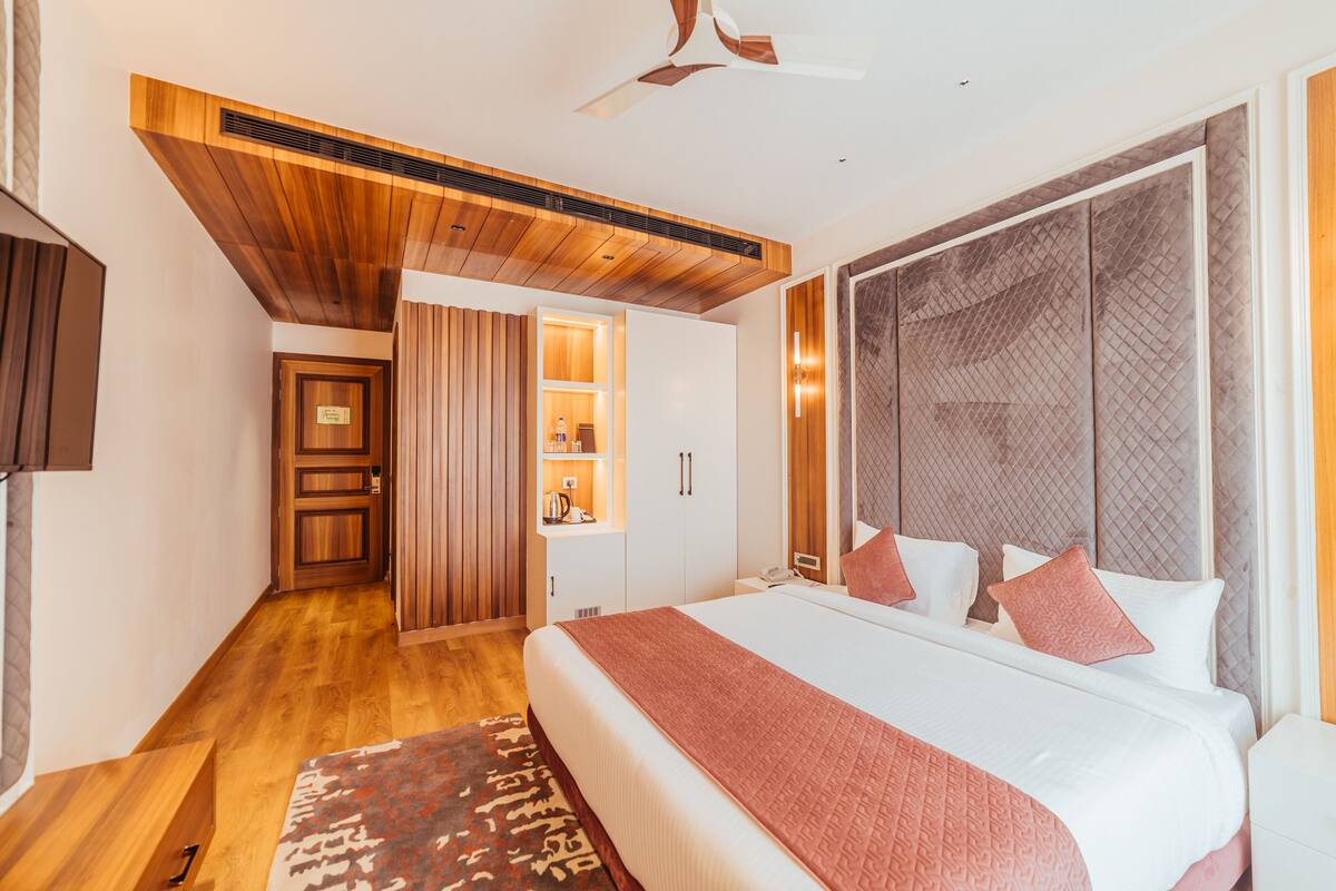 Ein modernes Hotelzimmer mit einem großen Bett, Holzboden und einem integrierten Kleiderschrank.
