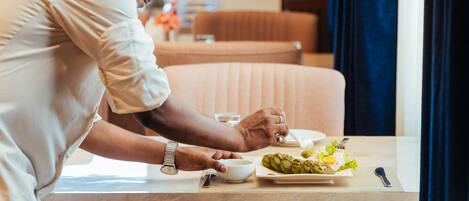 Une personne est assise à une table devant une assiette de nourriture, un bol et une cuillère.