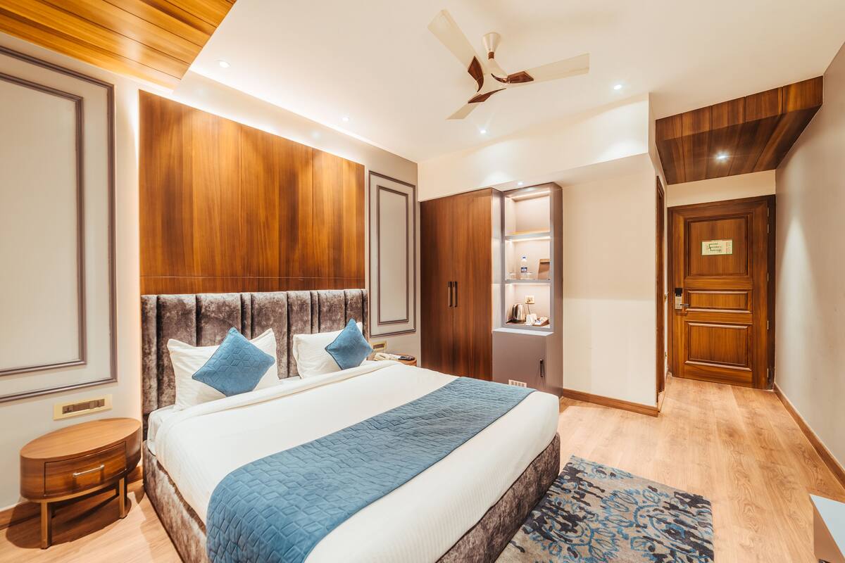 Ein modernes Hotelzimmer mit einem großen Bett, einem Holz-Kopfteil und einem eingebauten Kleiderschrank.