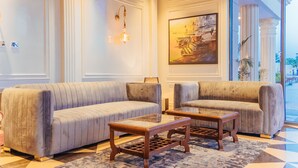 A lobby with two sofas, a glass-top coffee table, and a painting on the wall. - The Ramayana Hotel Ayodhya (Faizabad)
