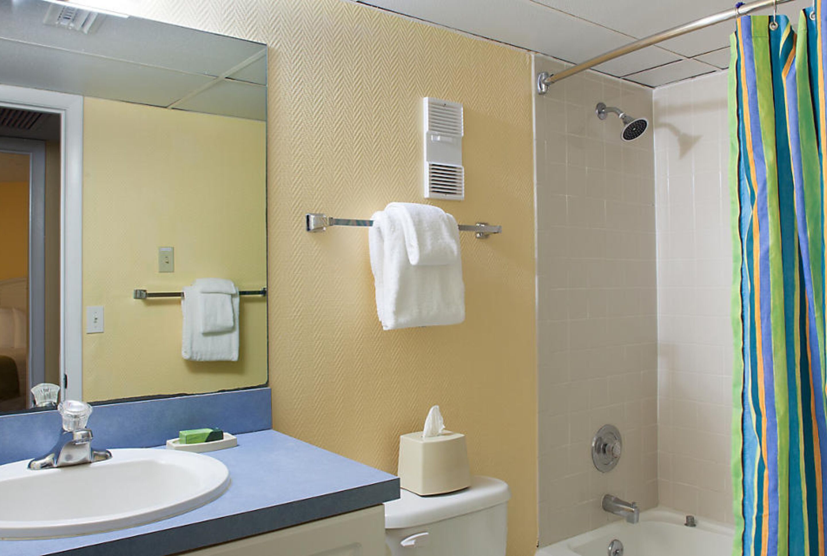 A bathroom with a sink, mirror, towel rack, and shower.