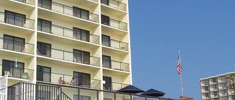 A multi-story hotel with balconies, a flag, and outdoor seating.