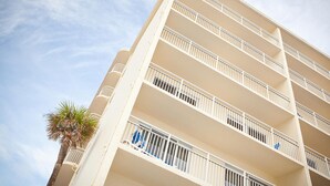 A multi-story hotel with balconies and a palm tree. - Fantasy Island II (Daytona Beach Shores)