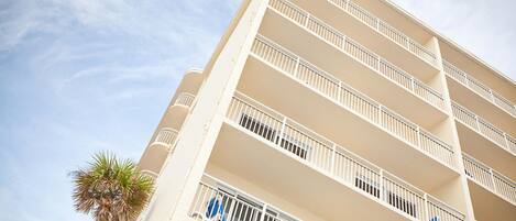 A multi-story hotel with balconies and a palm tree.