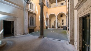 Une cour intérieure agrémentée d’une fontaine, de colonnes et d’une porte.