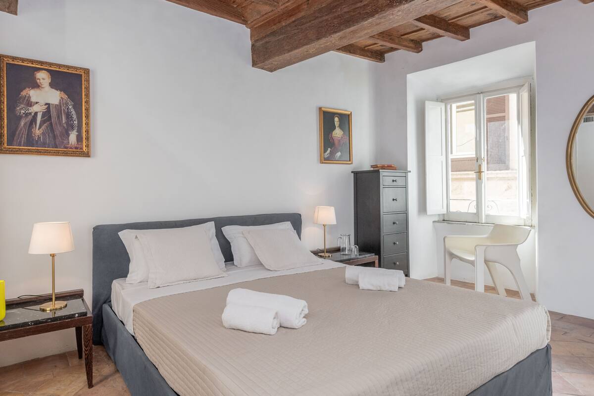 A bedroom with a bed, two bedside tables, a desk, and a chair.