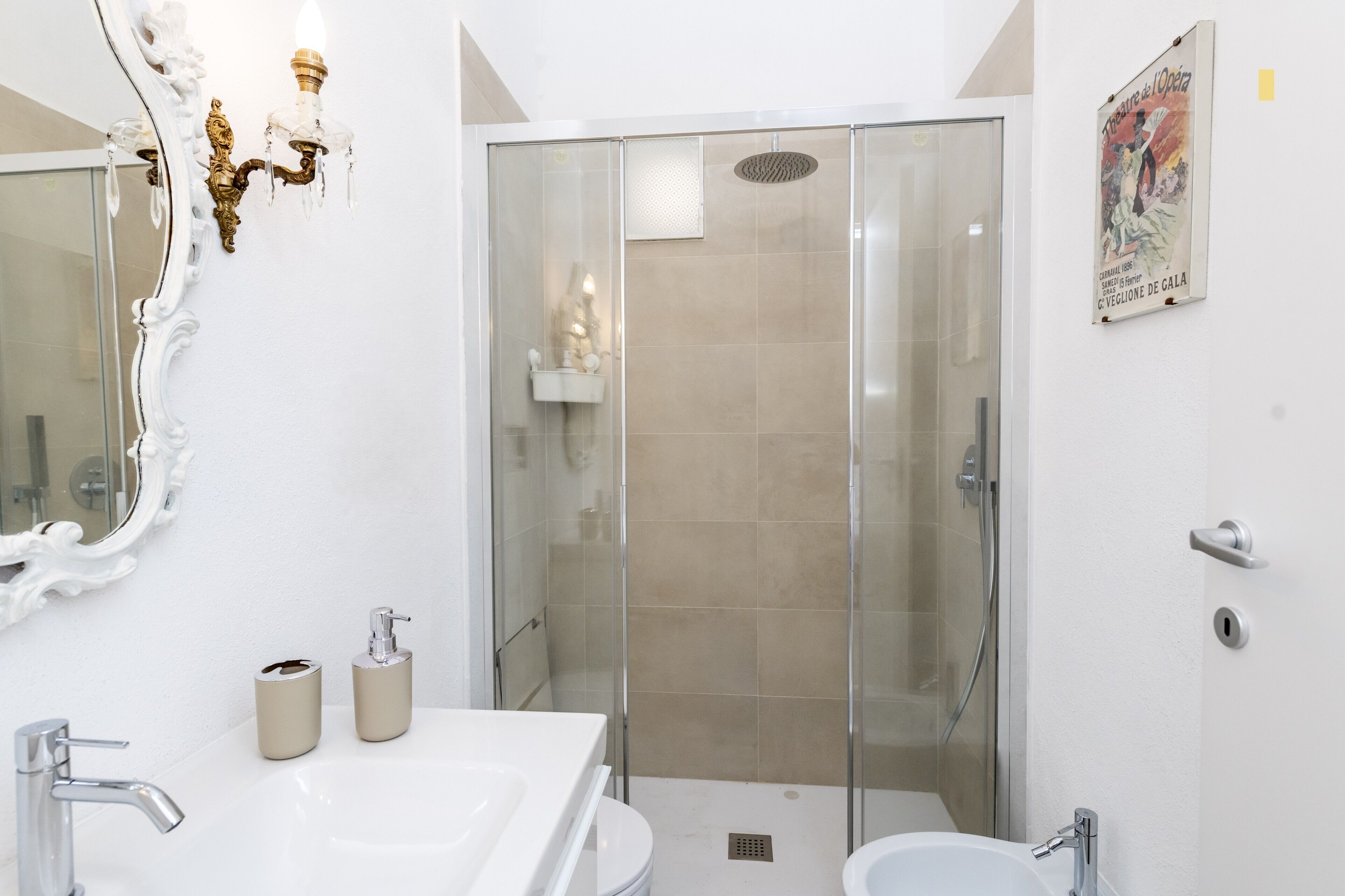 A modern bathroom with a glass-enclosed shower, a large mirror, and a white sink.