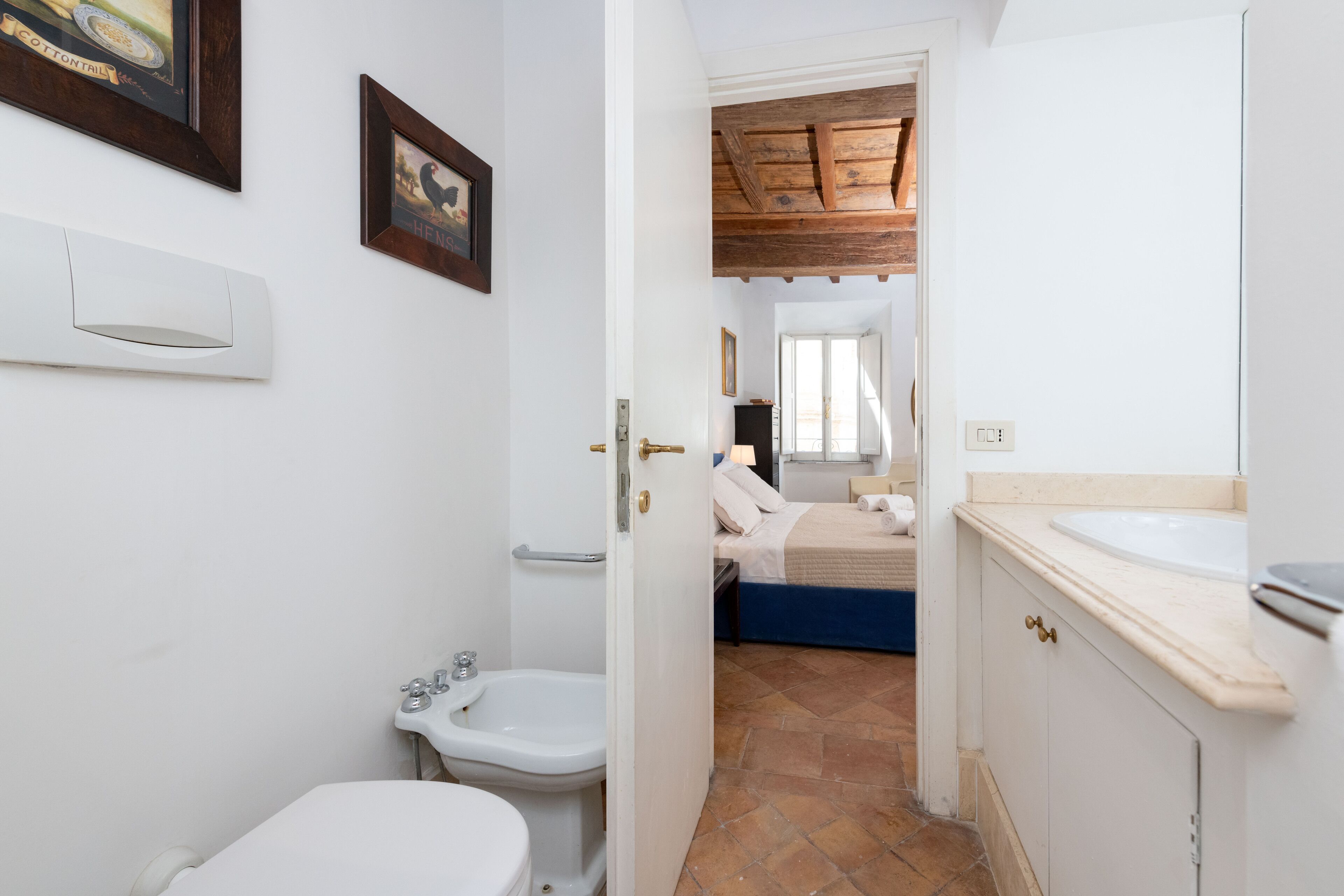 Un couloir  étroit mène à une chambre à coucher avec un lit, ainsi qu’à une salle de bain comprenant des toilettes, un bidet et un lavabo.