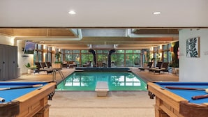 Un espace piscine comprenant une table de billard, des chaises longues et une vue sur l’extérieur.