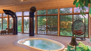 Un espace intérieur spacieux doté d’un jacuzzi, de grandes fenêtres et offrant une vue sur l’extérieur.