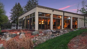 Un bâtiment moderne doté de grandes fenêtres, d’un chemin en pierre et d’une zone herbeuse.