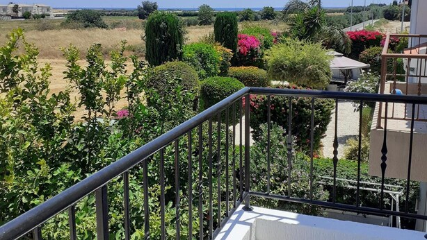 A balcony with a view of a garden and a distant landscape.
