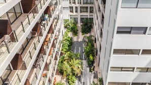 A multi-story building with a central courtyard featuring outdoor seating and greenery. - Ipana By Riviera Rentals (Playa del Carmen)