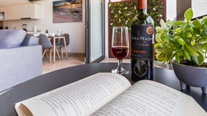 A modern living room with a dining area, a wine bottle, and a glass of red wine on a table. - Ipana By Riviera Rentals (Playa del Carmen)