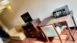 Ein kleiner Raum mit einem Holztisch, einem Fernseher und einer Mikrowelle.