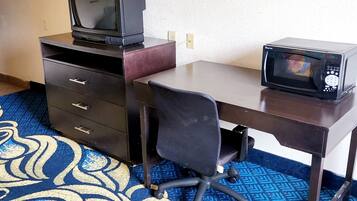 Una habitación de hotel con escritorio, televisor y microondas.