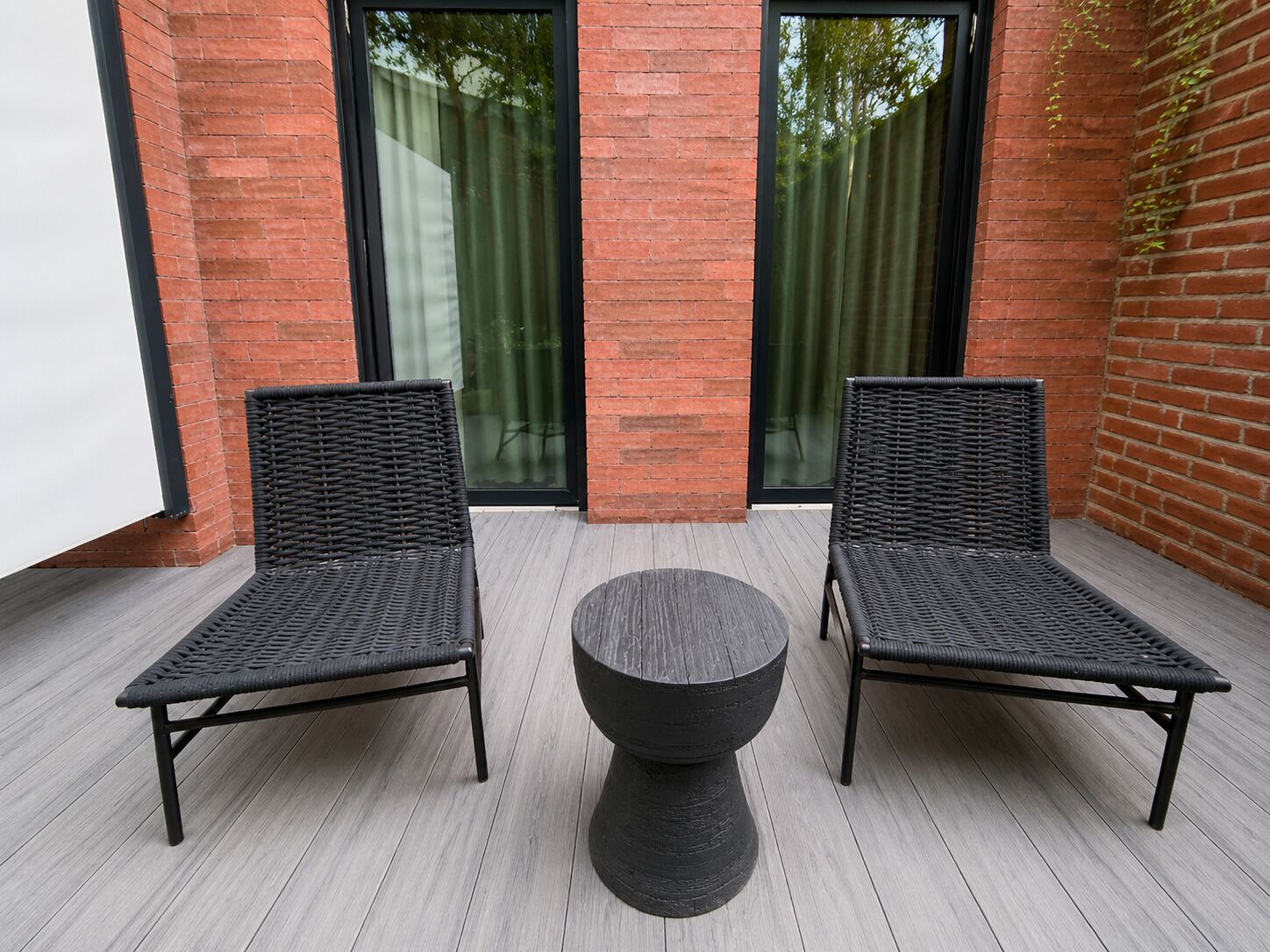 Un patio con dos sillas de mimbre y una mesa redonda.