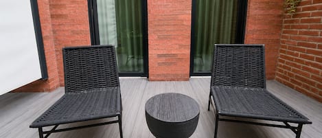 Un patio con dos sillas de mimbre y una mesa redonda.