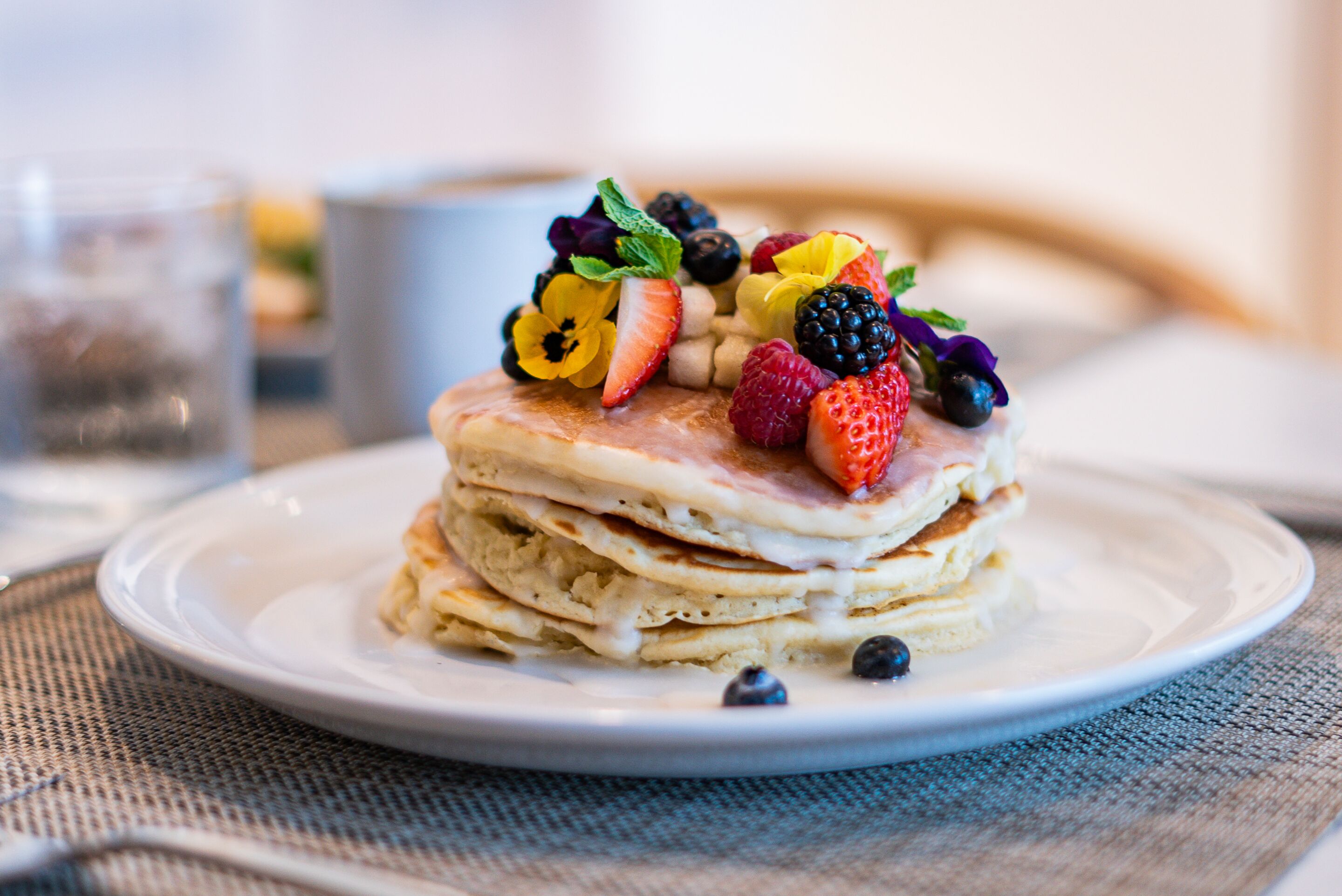 A stack of pancakes topped with various berries and a strawberry.