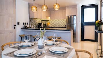 A modern kitchen with a central island, pendant lights, and a dining area with a round table set for four.