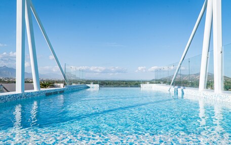 A clear blue pool with white pillars and a view of distant mountains.