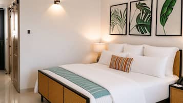A hotel room with a bed, a bedside lamp, and framed botanical artwork on the wall.
