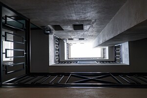 Un espacio arquitectónico moderno con techos de concreto, barandas de metal y tragaluces.