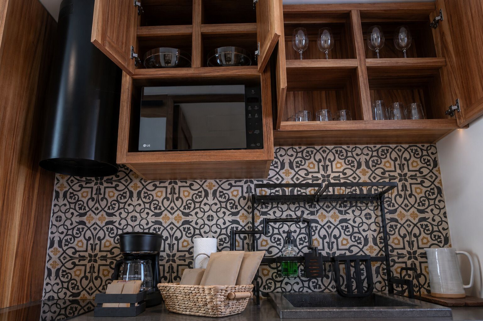Una cocina con microondas, cafetera y un colgador para vasos.