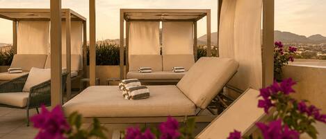 Zona relax sul tetto con diverse opzioni di seduta, tra cui poltrone e un divano, sotto una tenda.