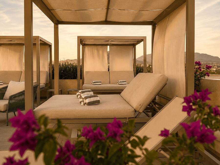 A rooftop lounge area with multiple seating options, including lounge chairs and a sofa, under a canopy.