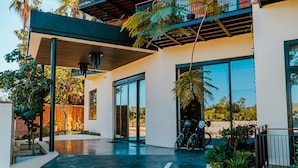 Un edificio moderno con un patio cubierto, ventanas amplias y una bicicleta estacionada afuera.