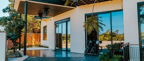 A modern building with a covered patio area, large windows, and a bicycle parked outside.