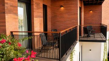 Un balcon avec une balustrade en bois, deux chaises et une table.