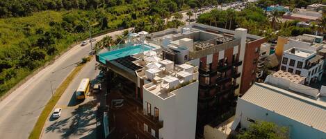 Un edificio moderno con piscina en la azotea y varios balcones.