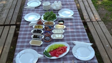 A picnic table set up outdoors with various food items and plates.