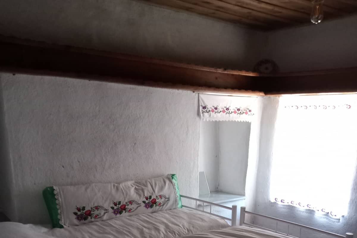Une chambre avec un grand lit, une petite table et une fenêtre avec des rideaux.