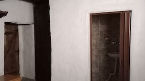 Una habitación con cama, puerta de madera, baño con lavamanos y una alfombra estampada.