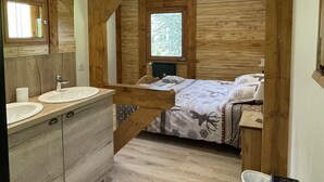 A modern bathroom with a wooden vanity, a sink, and a mirror. There is a window with a view of greenery outside.
