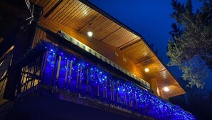A building with a wooden facade and a balcony adorned with blue lights.