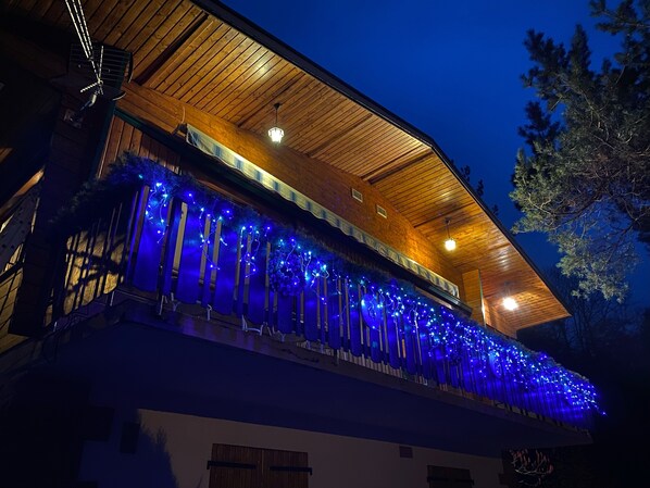 A building with a wooden facade and a balcony adorned with blue lights.