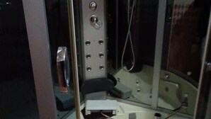 A small, enclosed shower area with a control panel, a handheld showerhead, and a handheld vacuum. - Jacuzzi city home free wifi, netflix (Kampala)