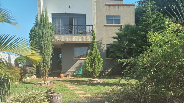 A modern two-story house with a balcony, surrounded by lush greenery and a well-maintained garden. - Jacuzzi city home free wifi, netflix (Kampala)