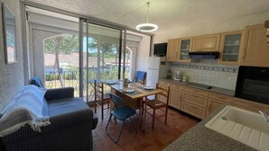 Een compacte keuken met een eethoek, een bank en een grote schuifpui naar een balkon.