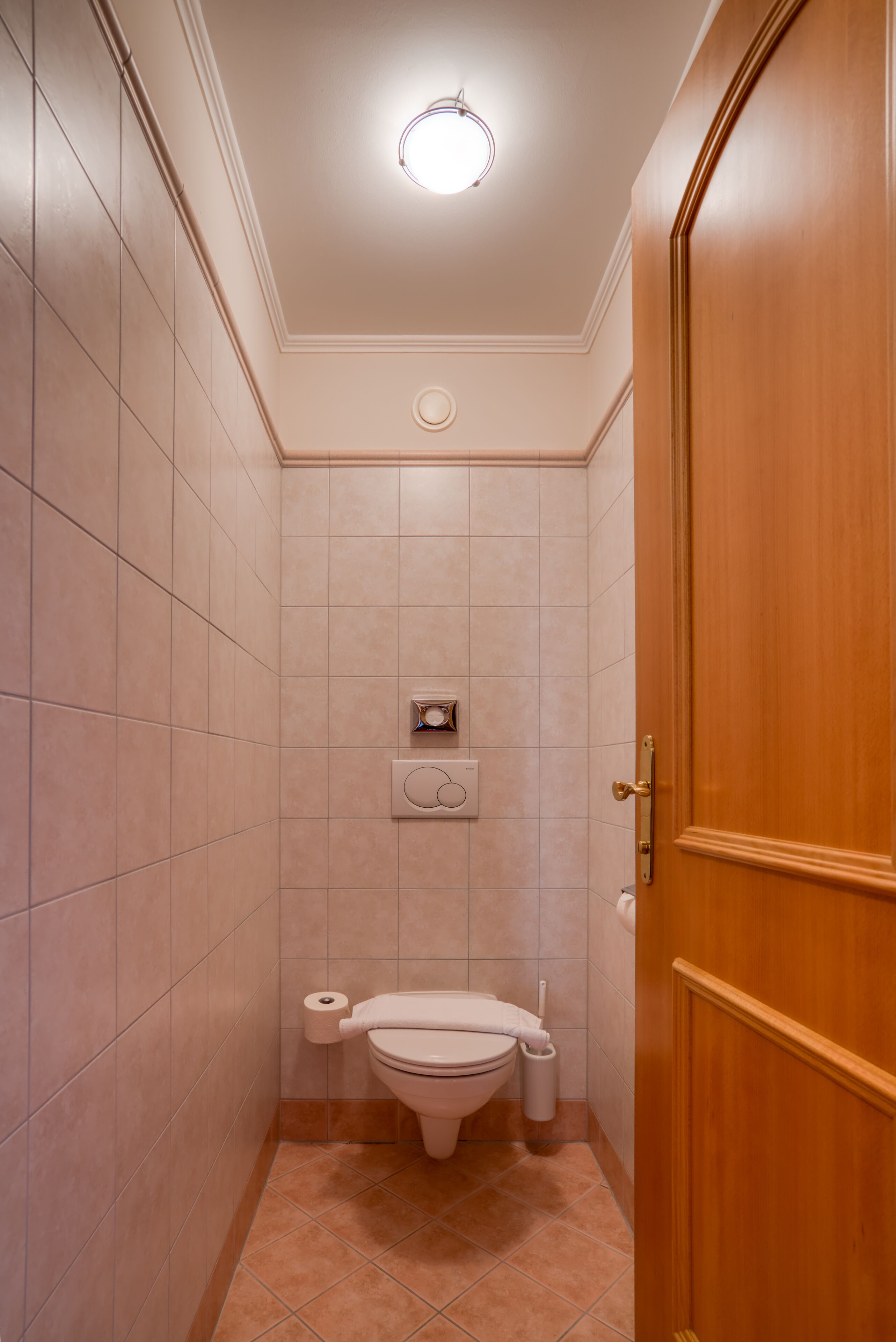 Een kleine badkamer met een toilet, een prullenbak en een handdoekhouder.