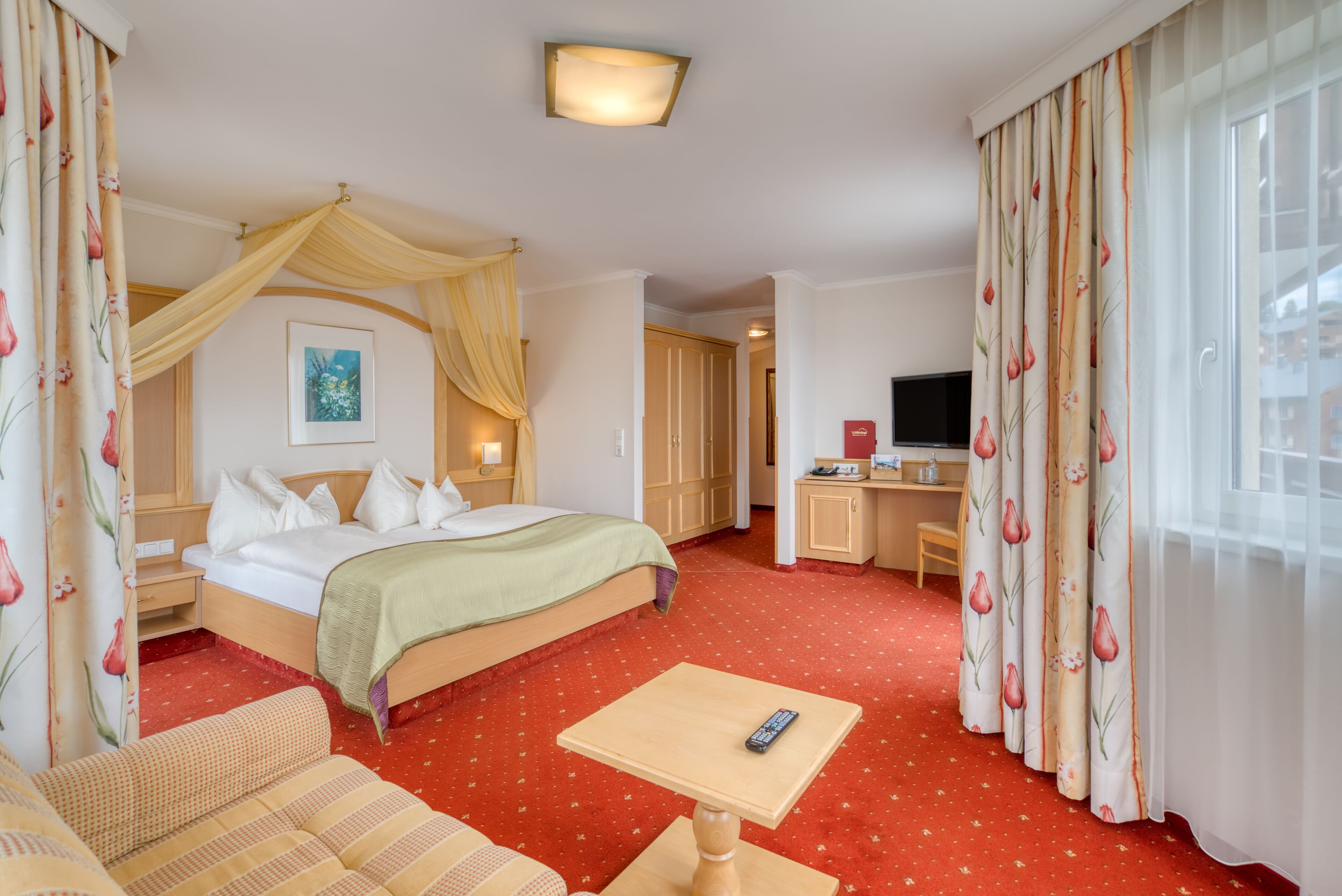 A hotel room with a bed, a desk, a sofa, and a TV.