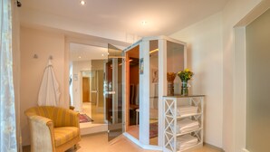 Una habitación con un armario de esquina, una silla, un tapete y un estante con toallas dobladas.