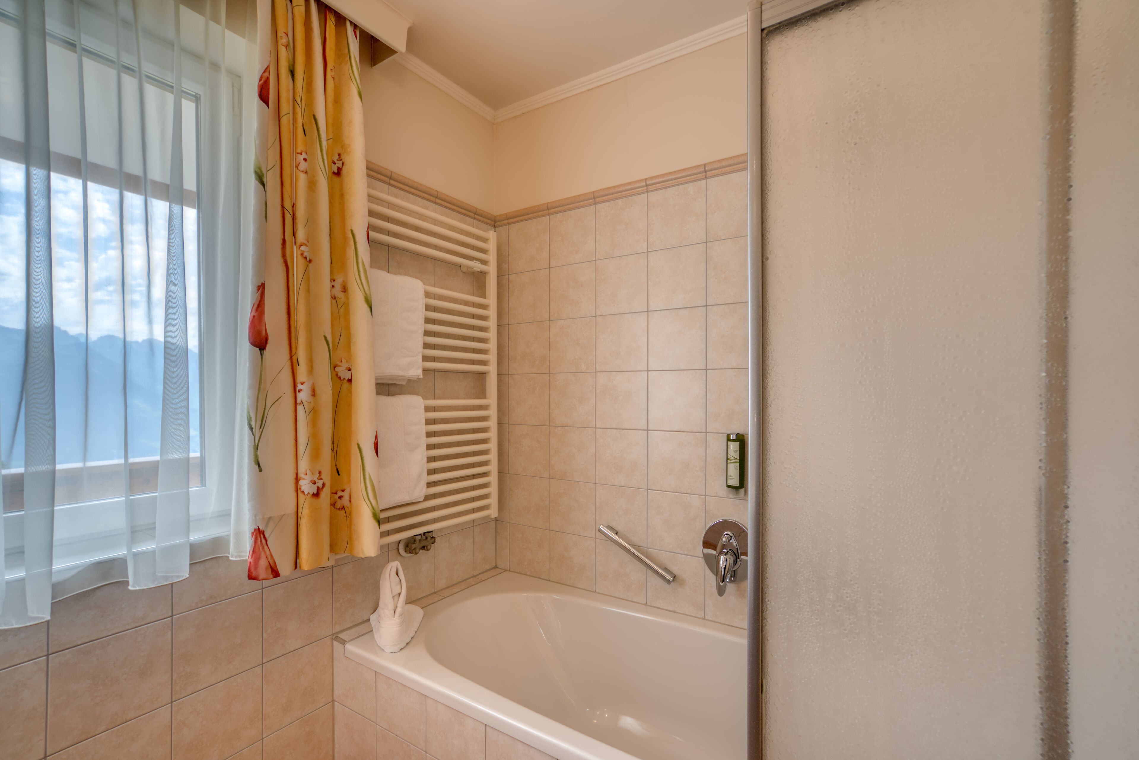 Un baño con bañera, toallero y cortina de ducha.