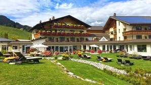 Un hotel con varios balcones, mobiliario exterior y un jardín bien cuidado.