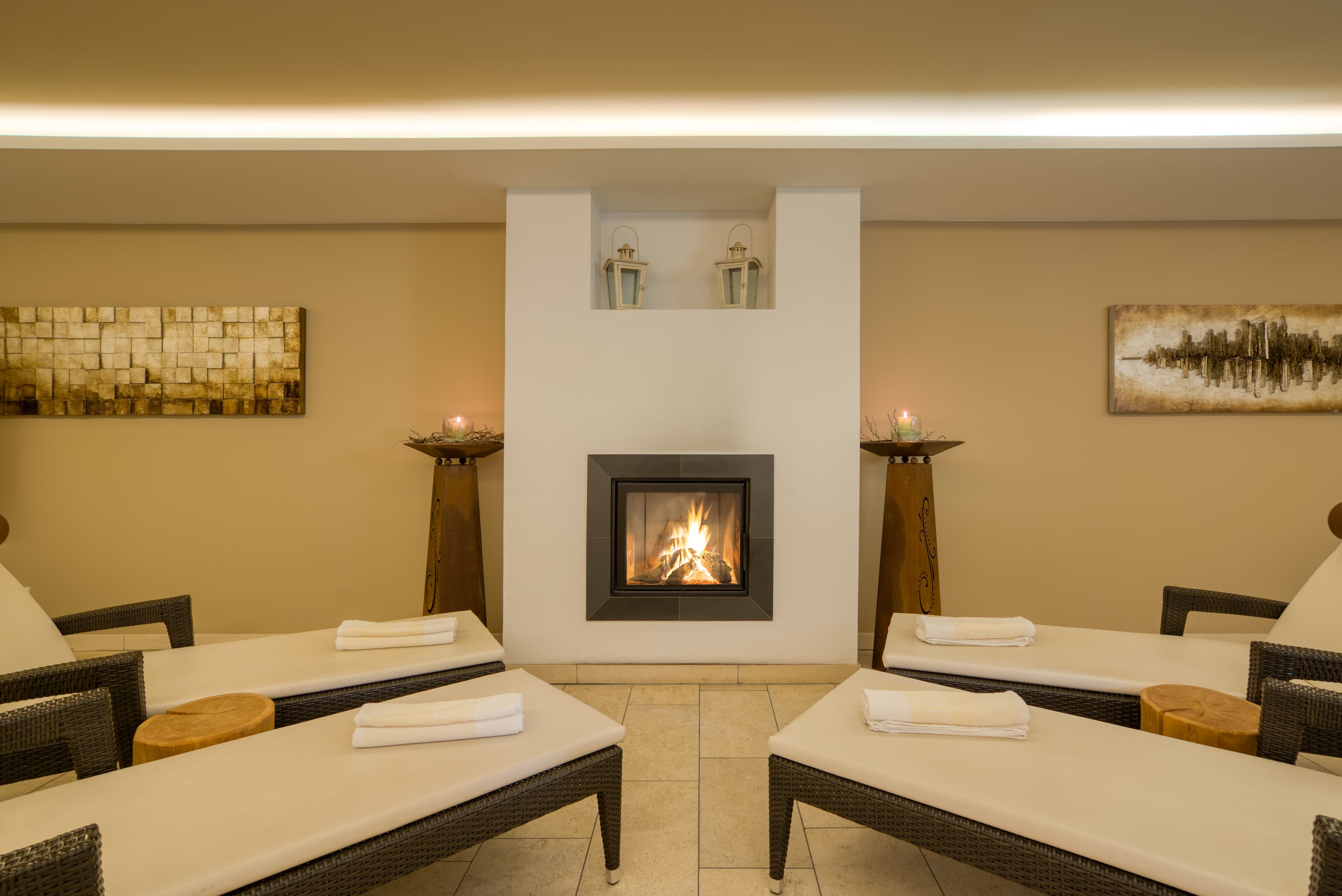 A spa area with two lounge chairs, a fireplace, and wall art.