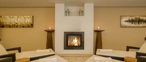 A spa area with two lounge chairs, a fireplace, and wall art.
